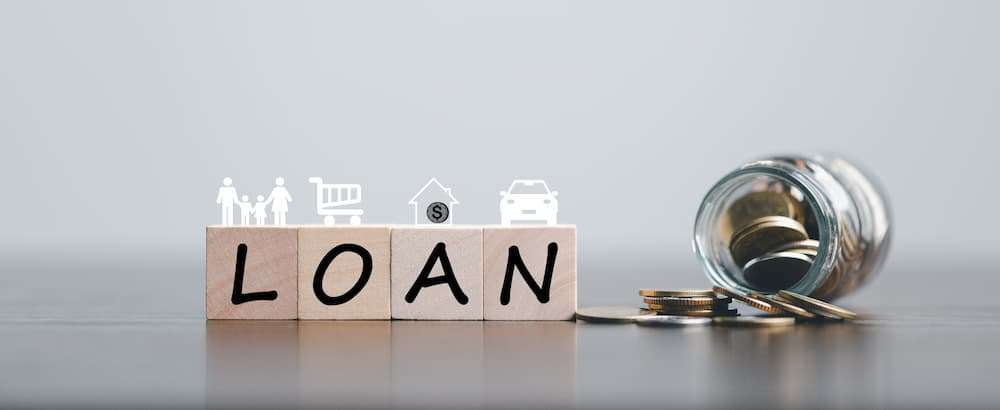 Wooden blocks spelling LOAN next to a jar of coins, representing unsecured loans from F&M Bank.
