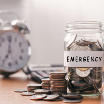Emergency fund jar filled with coins next to an alarm clock, representing financial security.