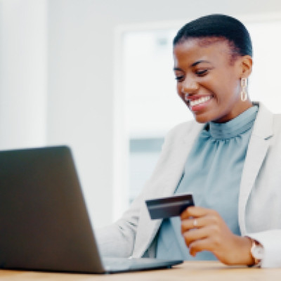 Businesswoman using a credit card on a laptop to illustrate how to build business credit.