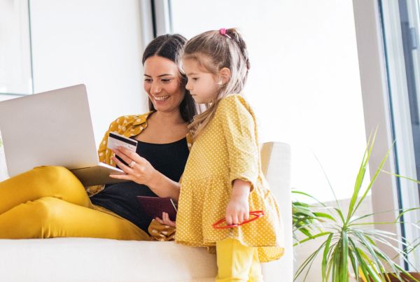 Mom holding debit card on laptop and sitting with child